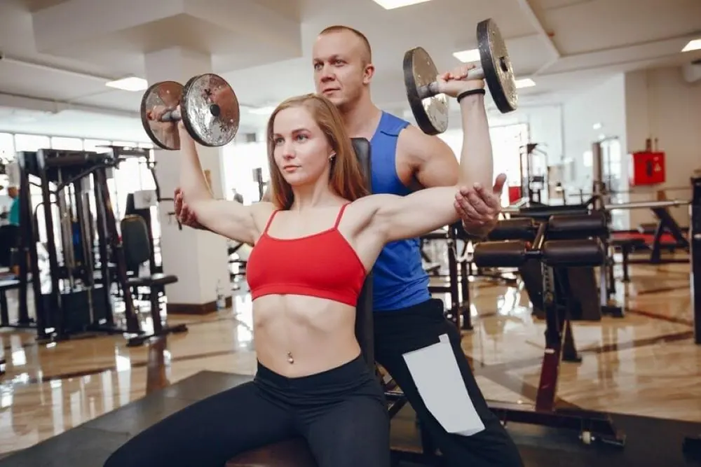 Gym instructor spotting a student