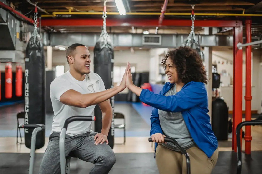 man and woman high five in the gym