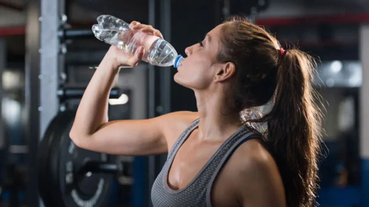 Woman drinking water during a gym workout