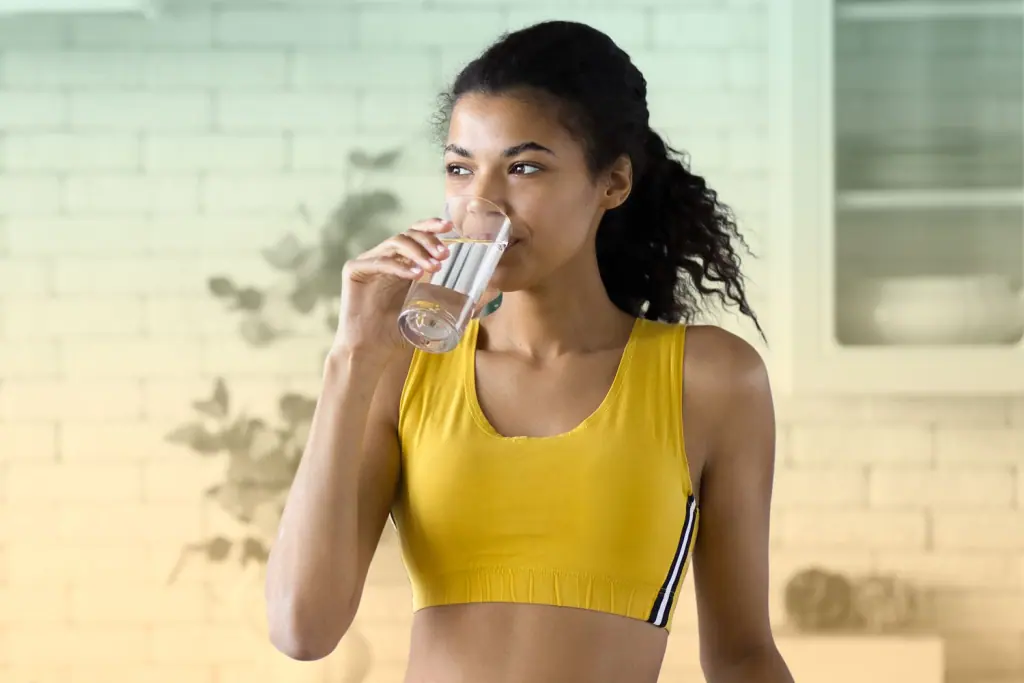 Woman drinking a glass of water after exercise